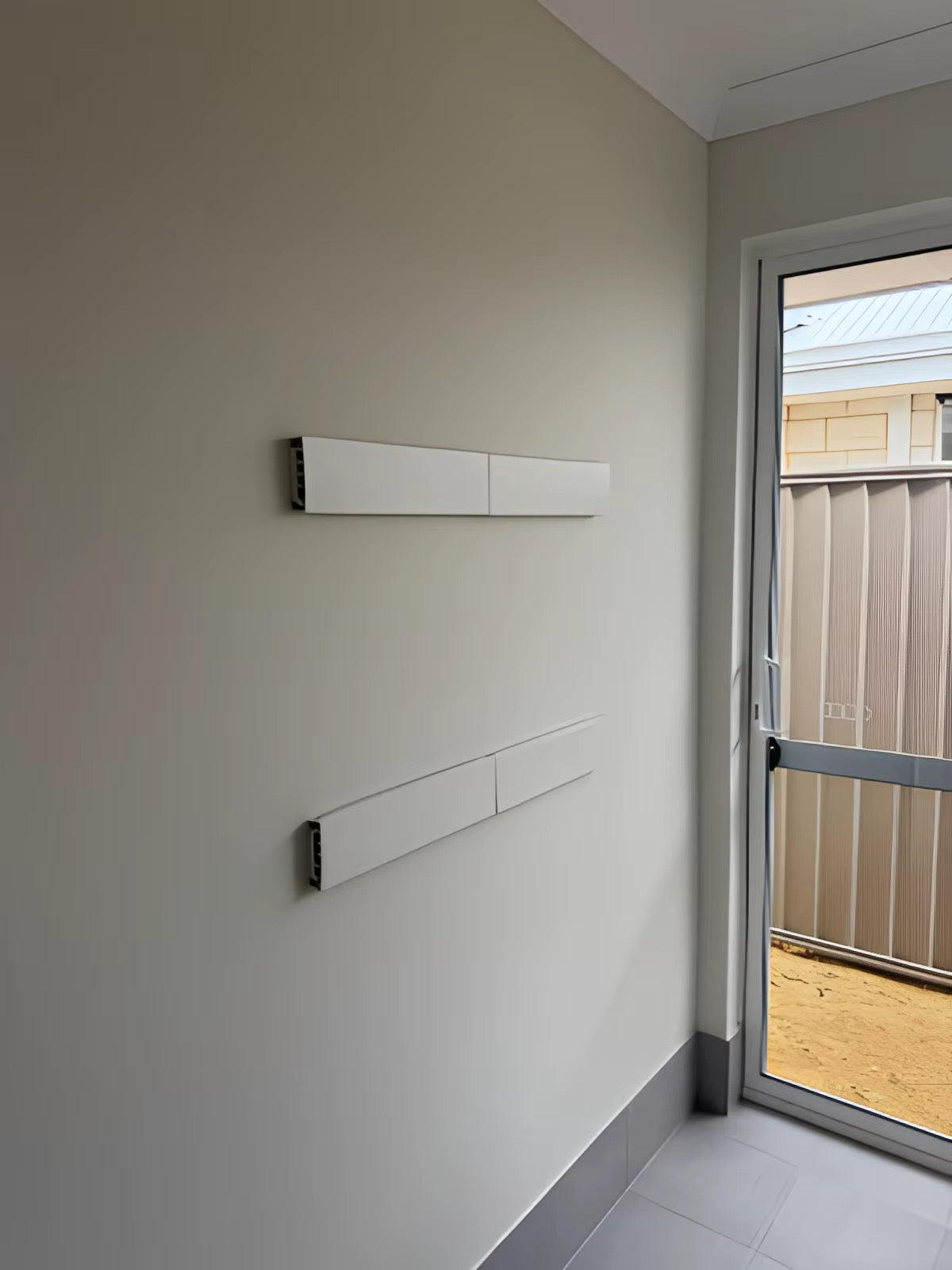 Clothes hanging on wall-mounted drying rack in bright laundry room
