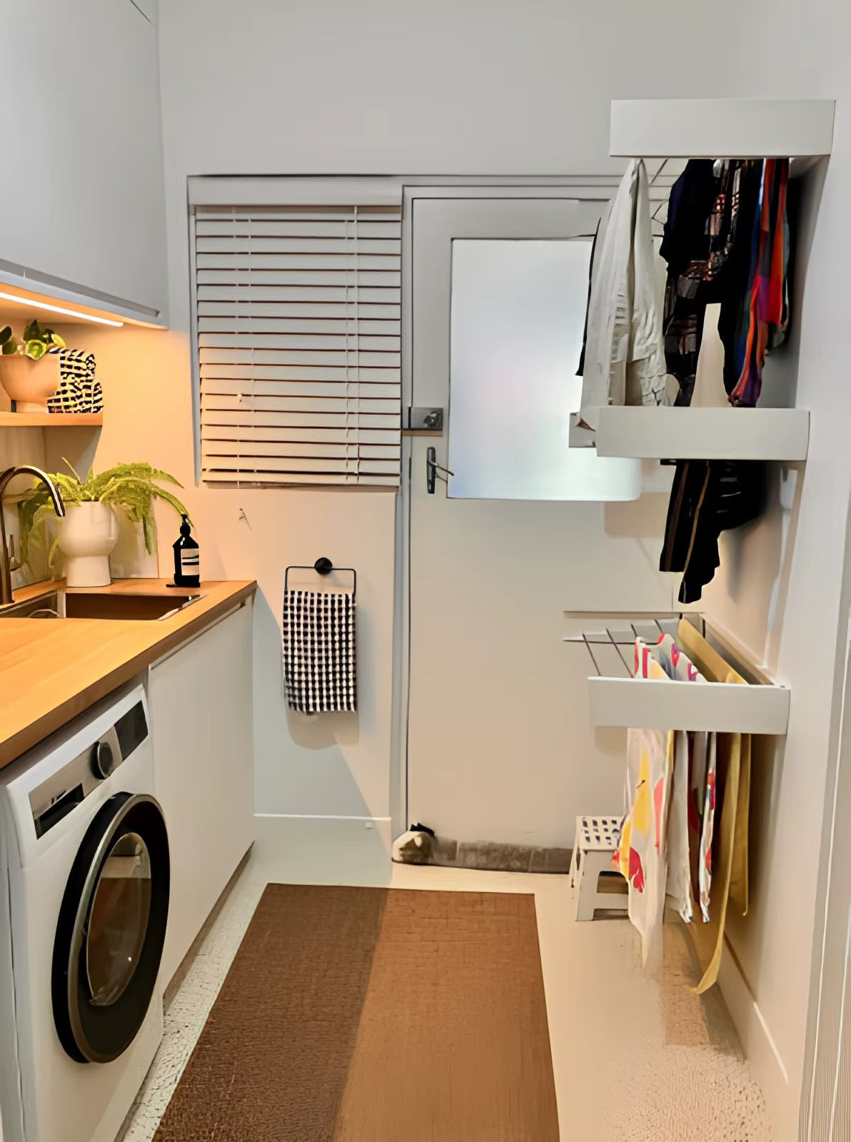 Multiple wall-mounted drying racks installed in a modern laundry room